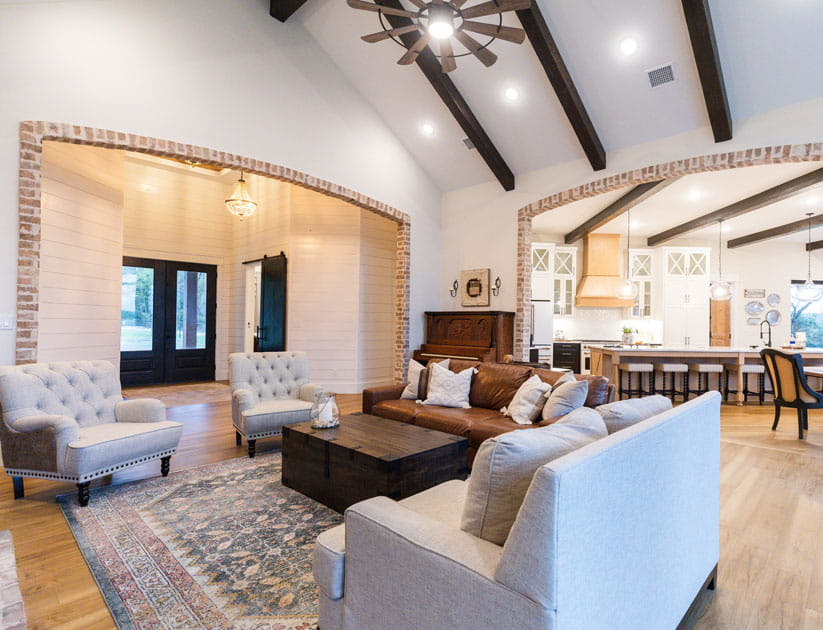 Neat and clutter free living room with brown leather sofa, neutral accents, and brick accents.