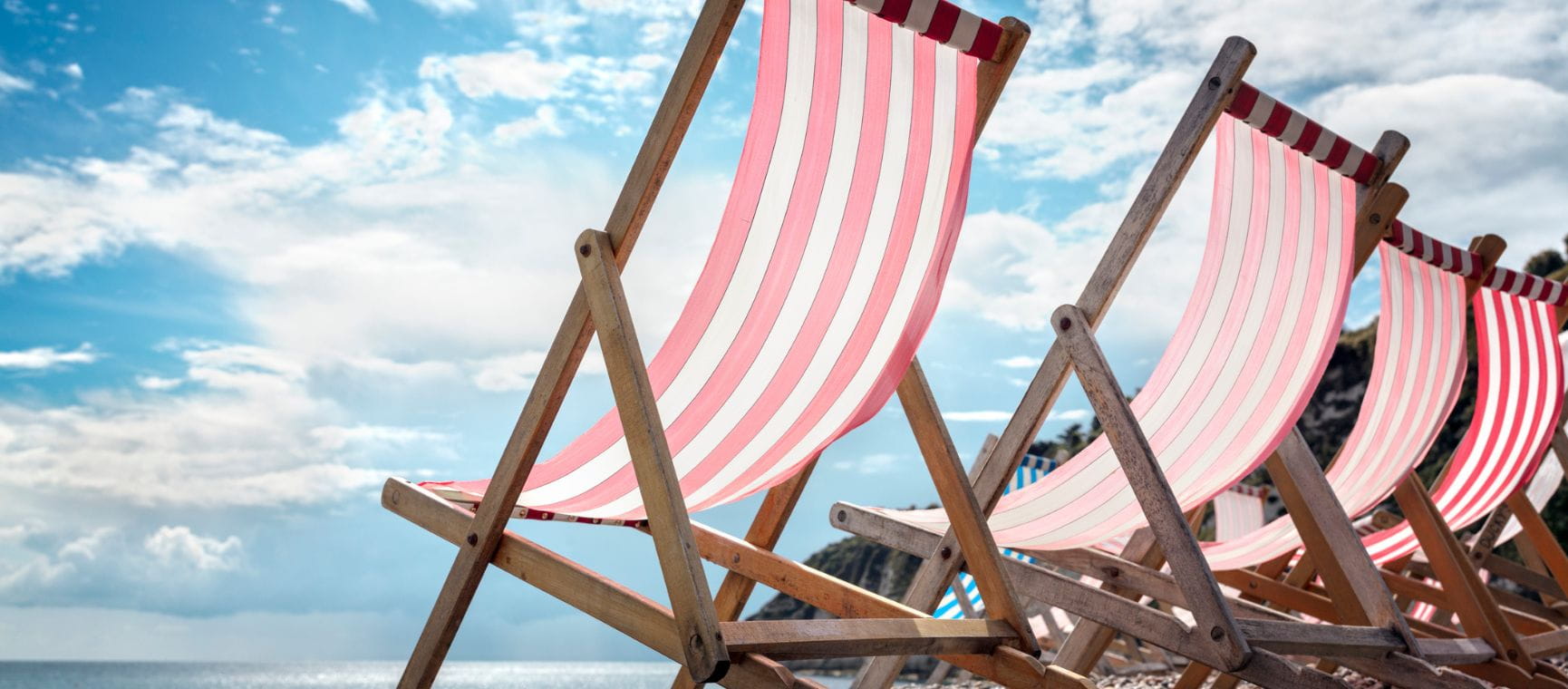 a row of red and white striped deckchairs with a blue sky backdrop