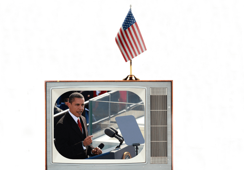 An old fashioned TV with an American Stars and Stripes flag on top showing Barack Obama at his inauguration