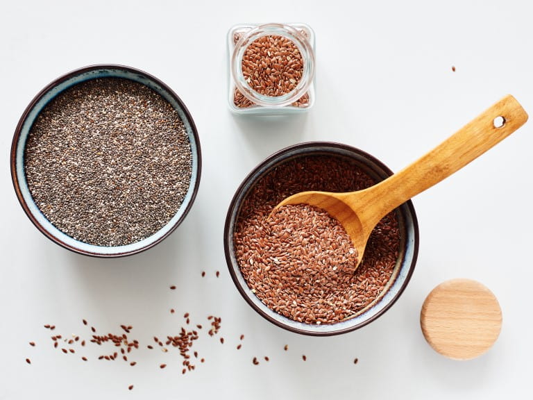 Flax seeds and chia seeds in bowls, top view