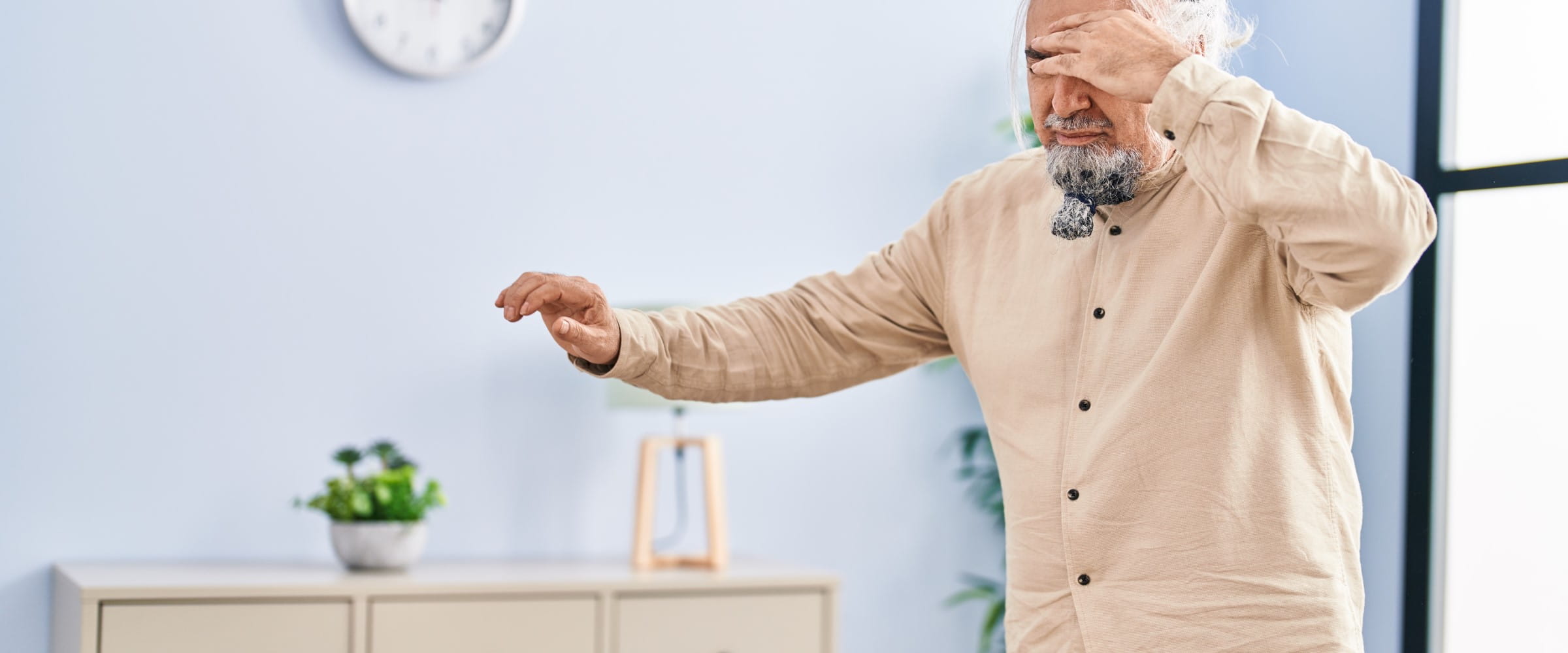 Middle age grey-haired man suffering dizzy standing at home | Getty/AaronAmat