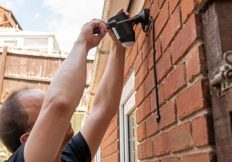 A man installing an external security light