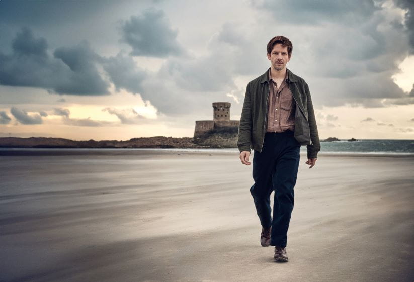 Damien Molony as Jim Bergerac walking across the beach