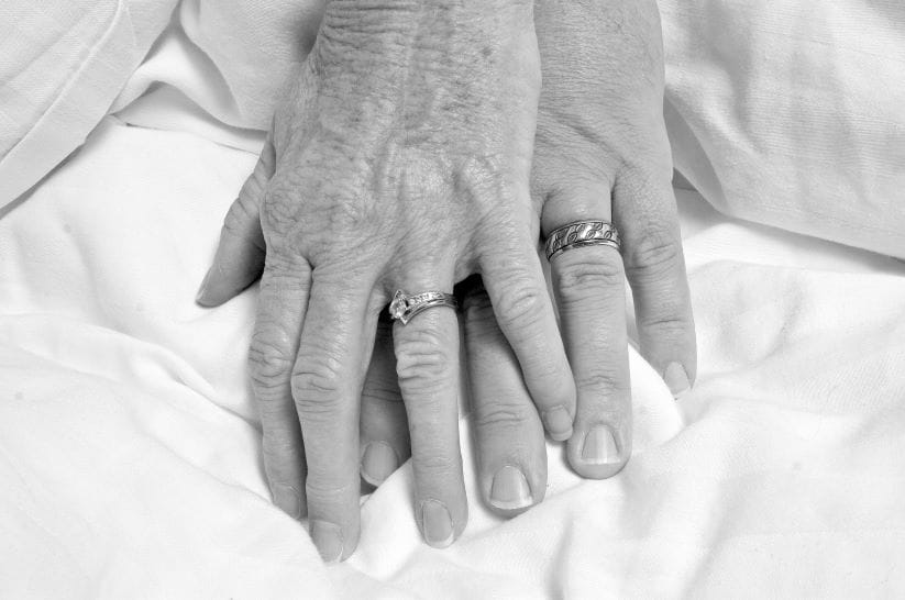 Two hands clasped in love, with diamond rings