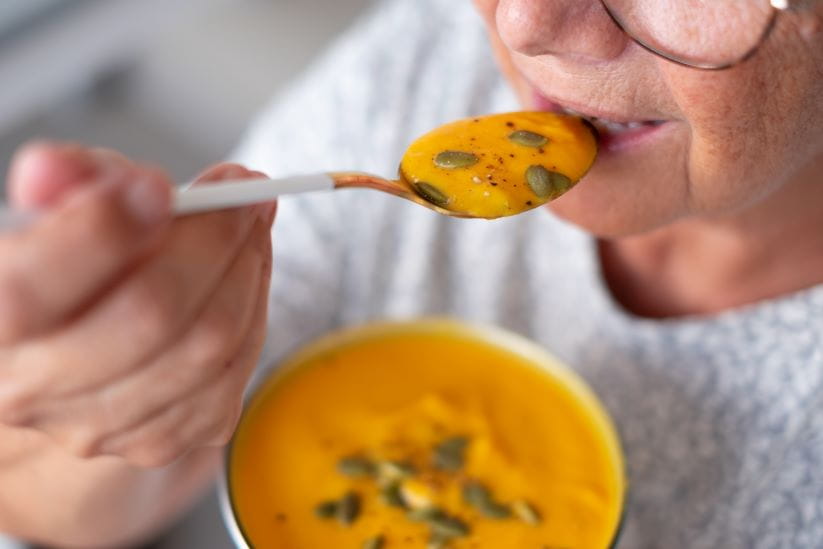 Woman eating hearty soup to stay warm