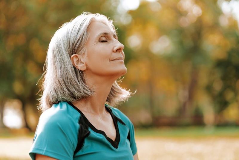 A woman outside with her eyes shut taking a breath