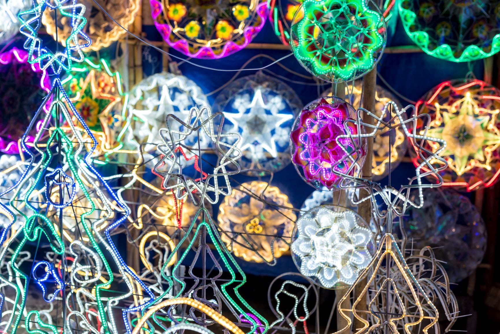 Colourful modern Christmas lanterns made with wire and LED wall strips hanging on a fence. Known locally as parols for sale during the xmas season.