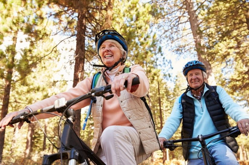 A man and a woman riding bikes in a forest