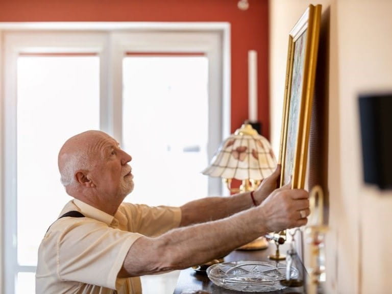 Man rearranging pictures on a wall