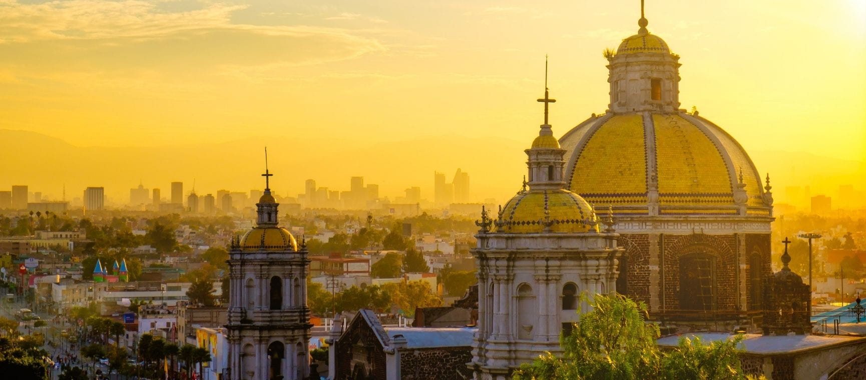 a view over Basilica of Guadalupe with Mexico City skyline at sunset