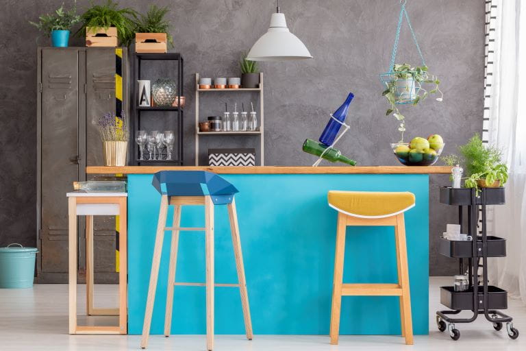 a modern kitchen with breakfast bar beneath free standing stairs