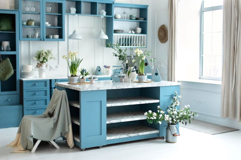a modern kitchen with breakfast bar beneath free standing stairs