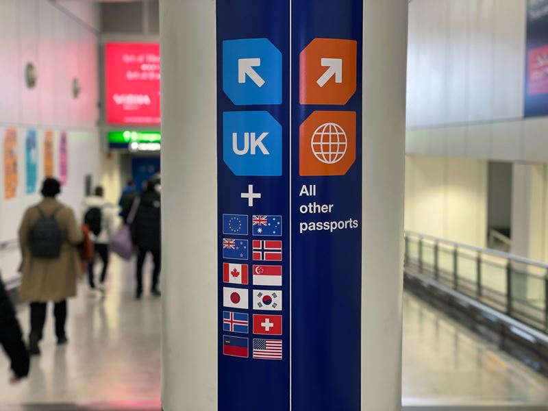 Airport sign showing UK passports one way and EU the other