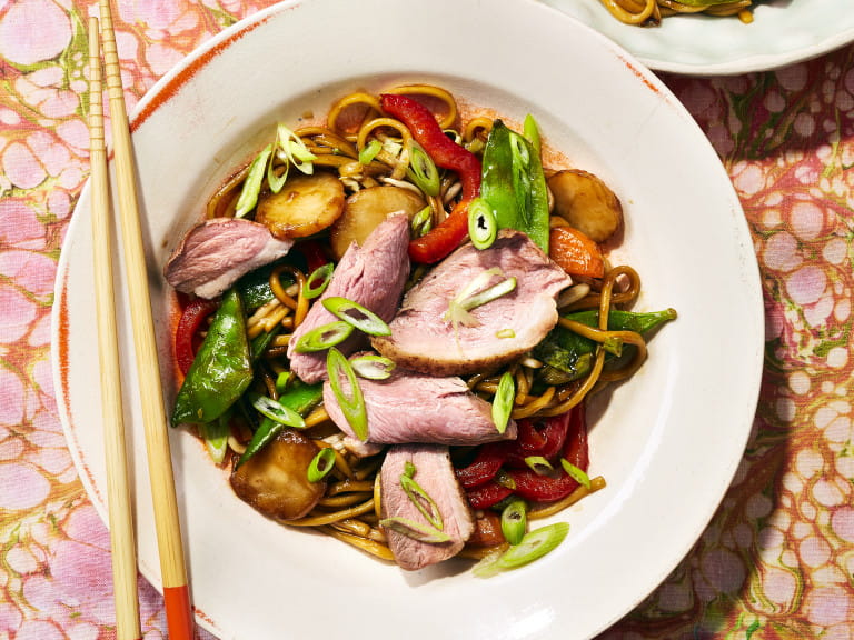 A white plate with teriyaki duck breast noodles