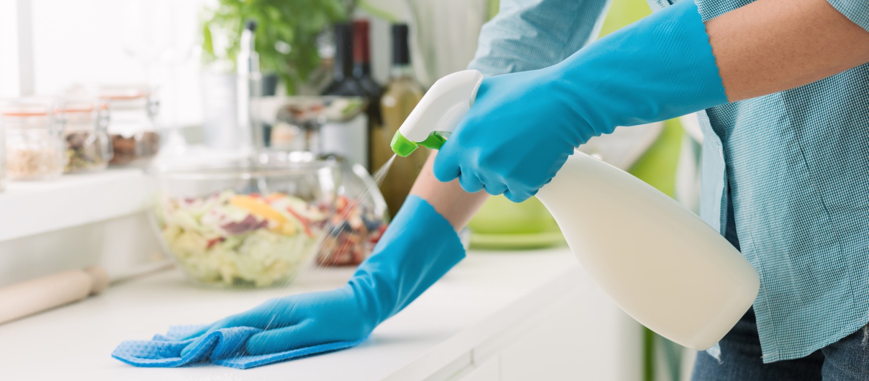 hands in blue gloves cleaning a kitchen worksurface