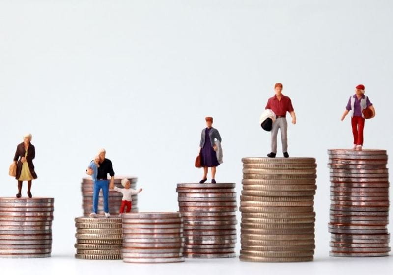 toy family miniature figures standing on piles of coins