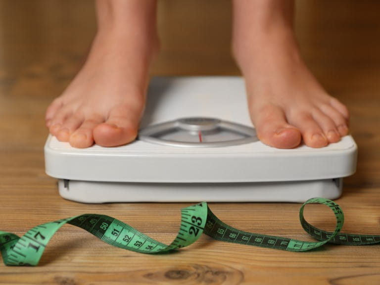 A woman standing on some scales next to a tape measure