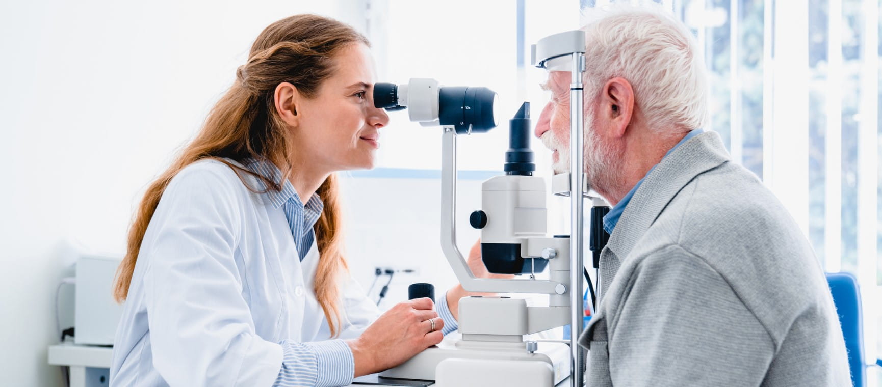 An optician checks the eyes of an older patient