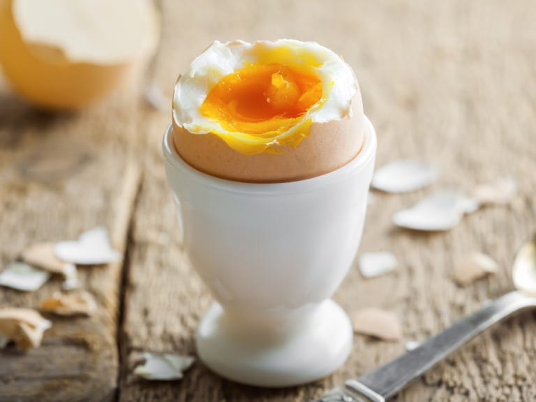 A boiled egg with the top removed and runny yolk