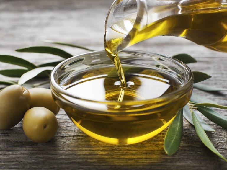 Olive oil being poured into a glass bowl