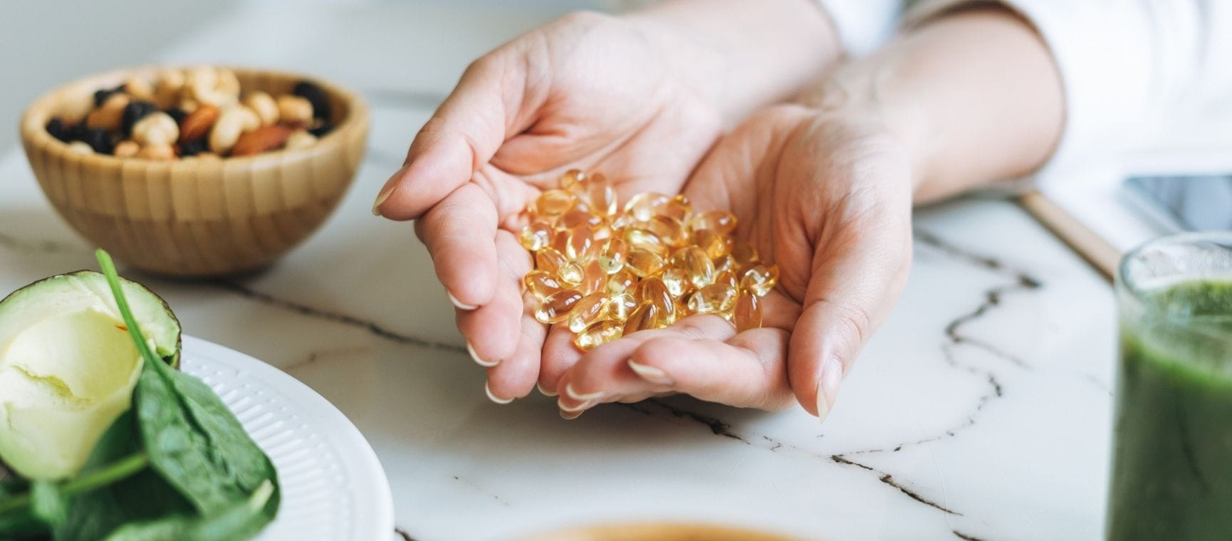 a woman holding a handful of omega 3 supplements with foods containing it around her