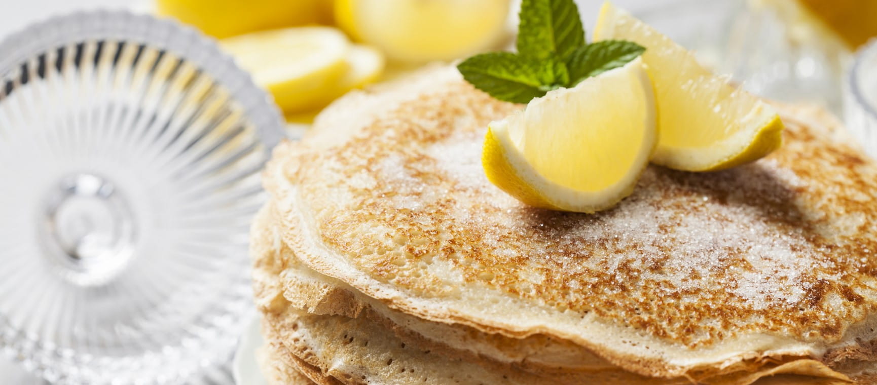 Pancakes dusted with sugar and topped with slices of lemon