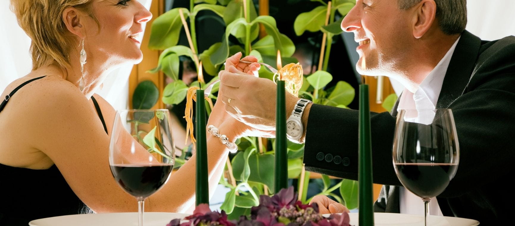 A couple enjoying a candlelit dinner feeding each other