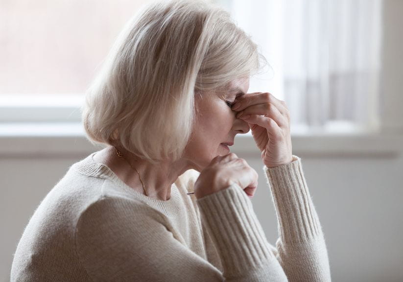 A woman pinching her nose and looking down like she's stressed