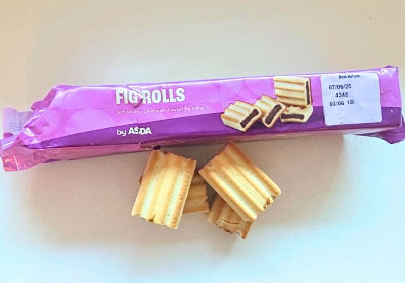 A packet of fig rolls with some loose fig roll biscuits by the side shot on a white background