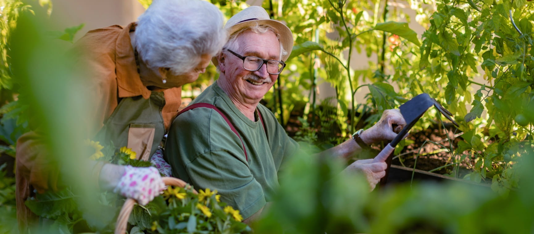 A senior couple tending plants in raised beds using accessible gardening tools