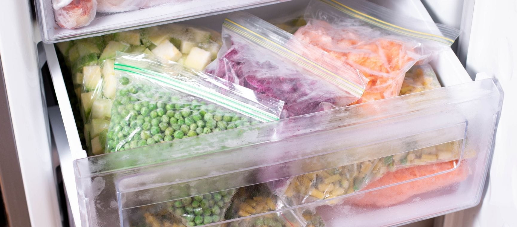 An image of an open freezer drawer containing various vegetables and foods