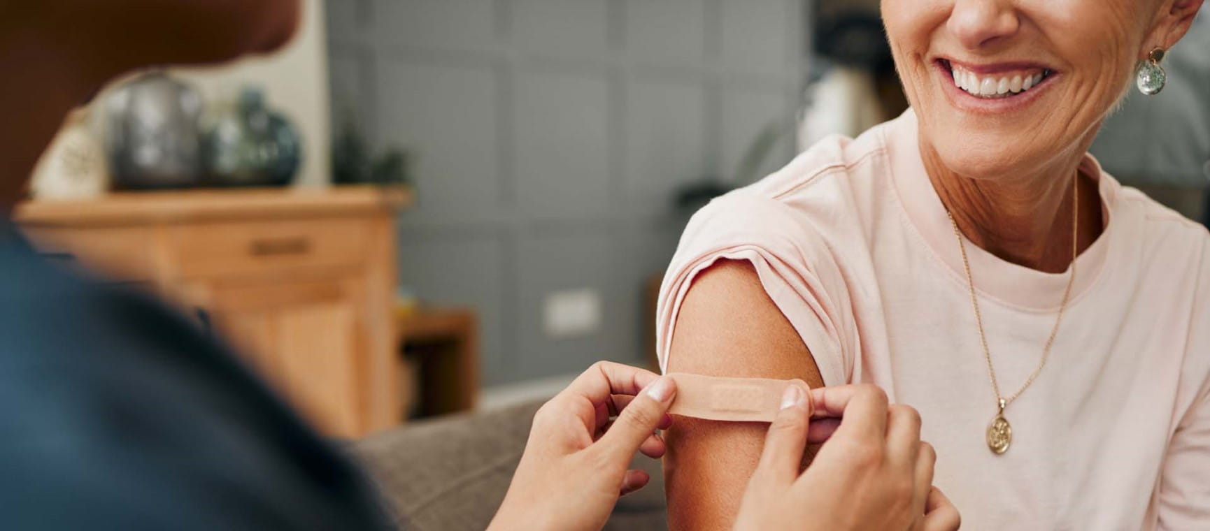 A laughing woman having a plaster applied by a nurse