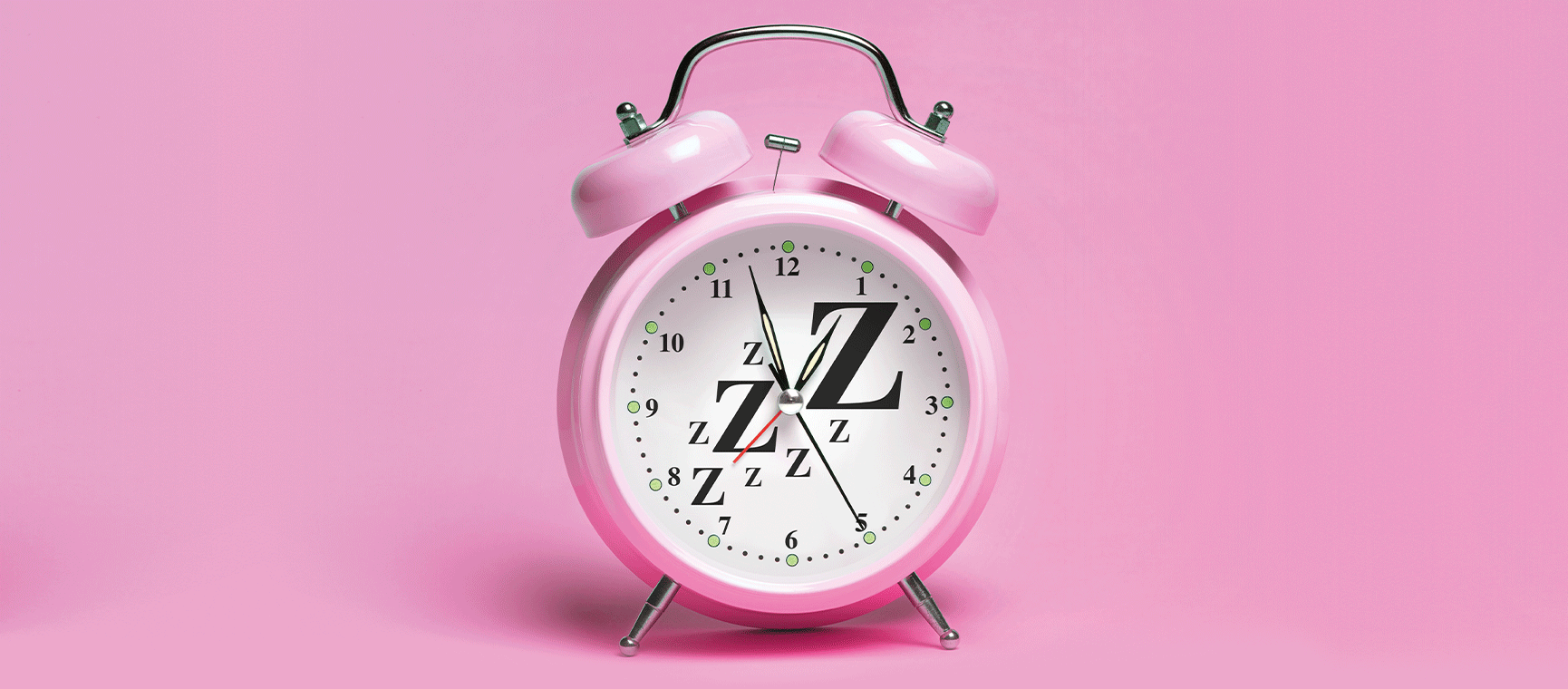 A pink alarm clock on pink background with many z's on its face