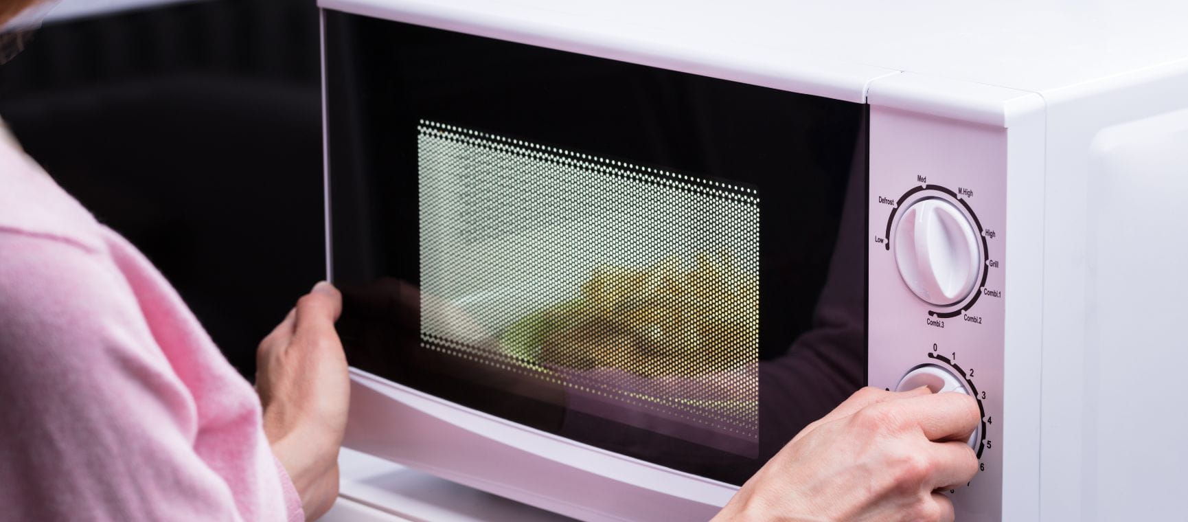 A woman heating up some food in a microwave