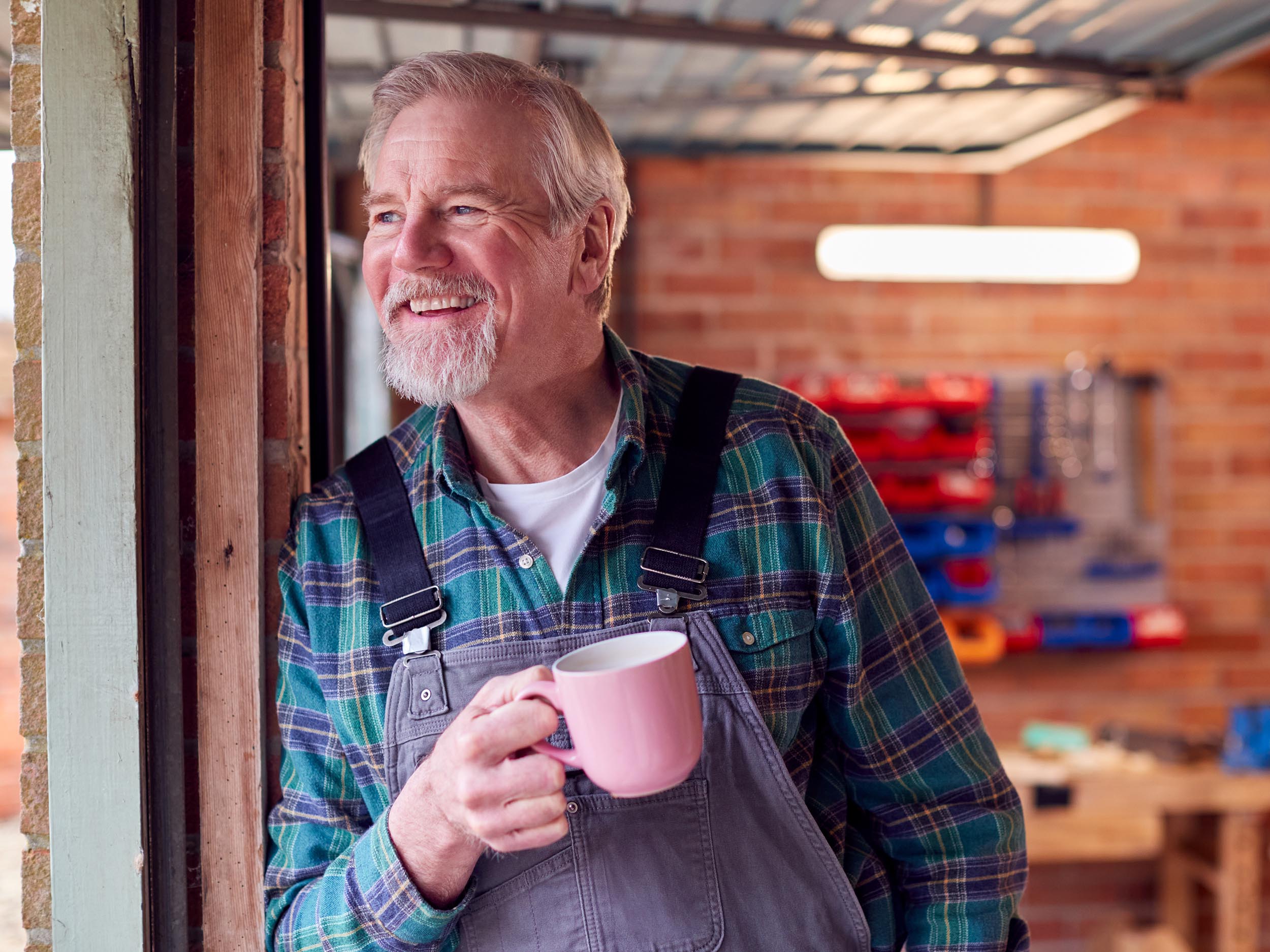 An older man with a cup of tea smiling