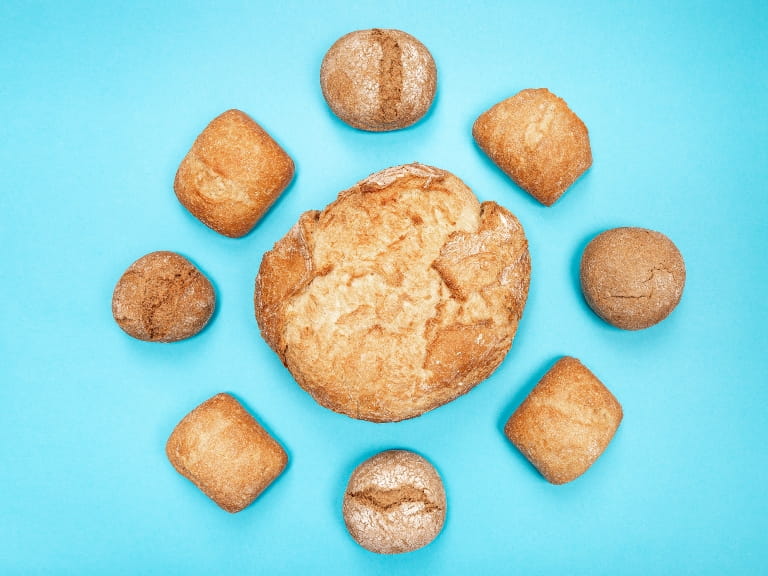 A large loaf of bread surrounded by smaller loaves on a blue background