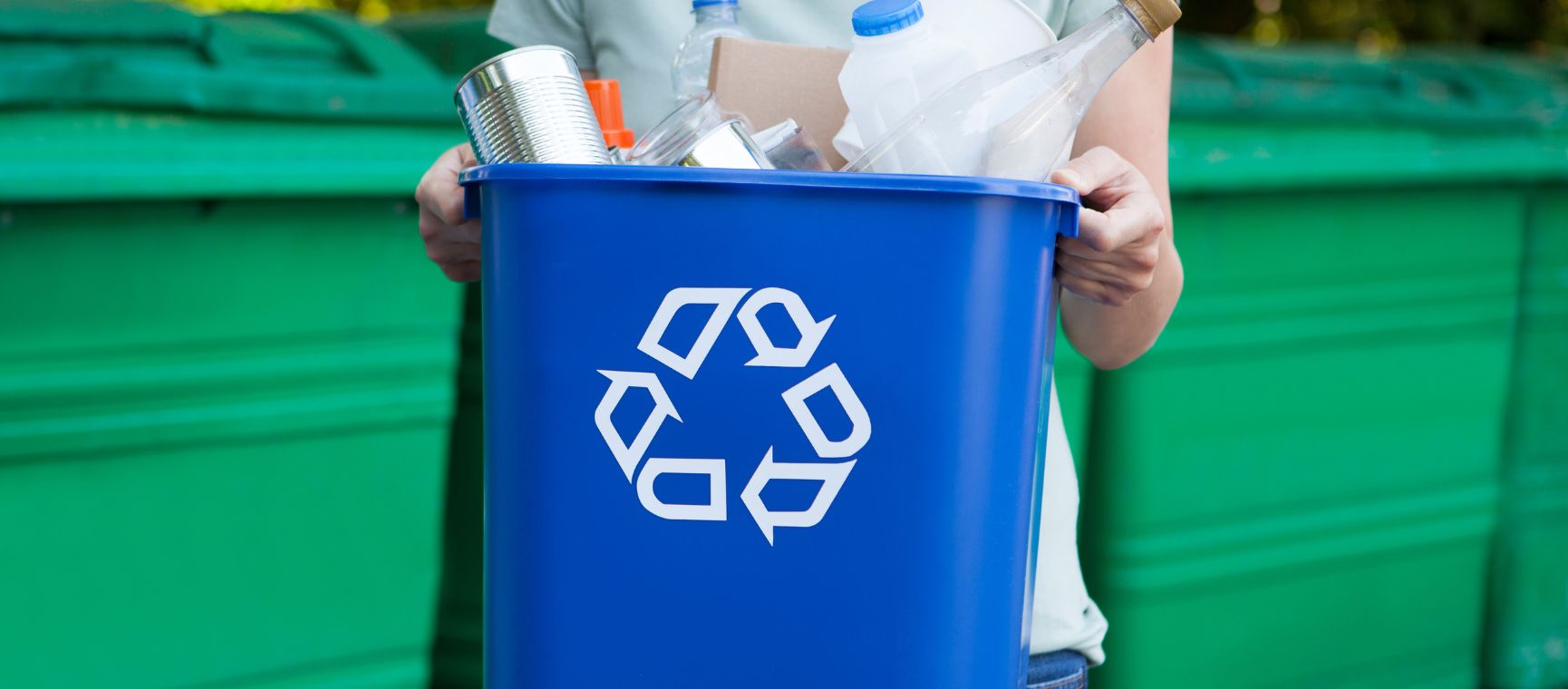 Someone holding a blue recycling bin full of recyclable materials