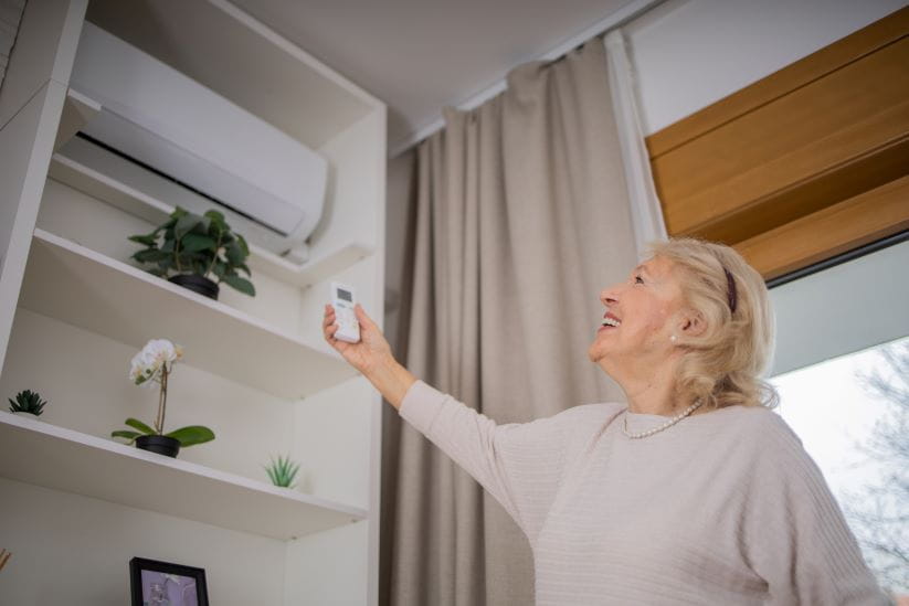 Woman turning on the air conditioning at home