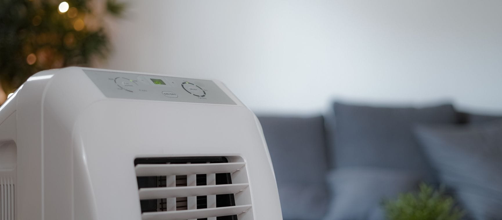 A portable air conditioning unit next to a sofa