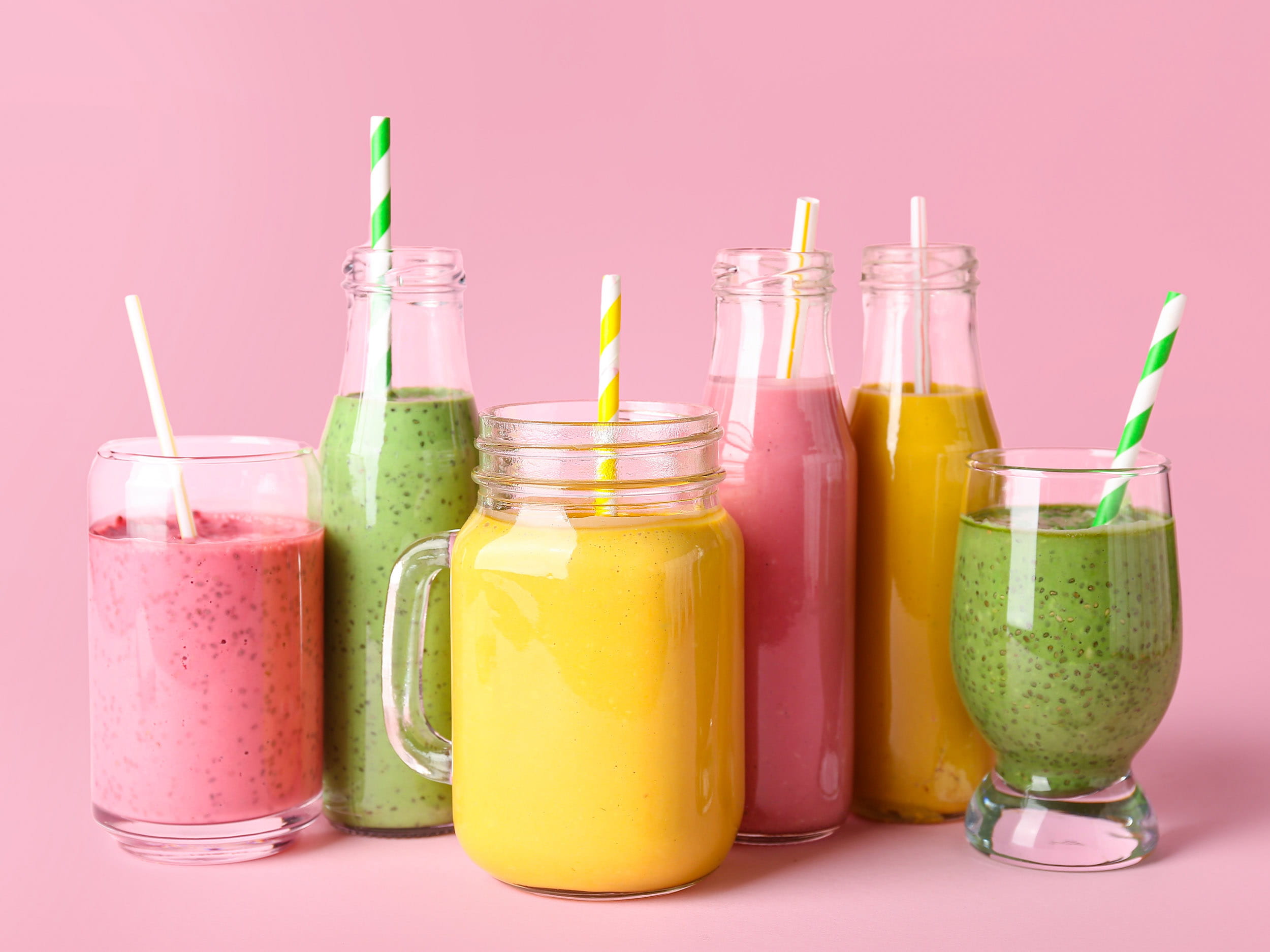 A variety of fruit smoothies in glasses with straws