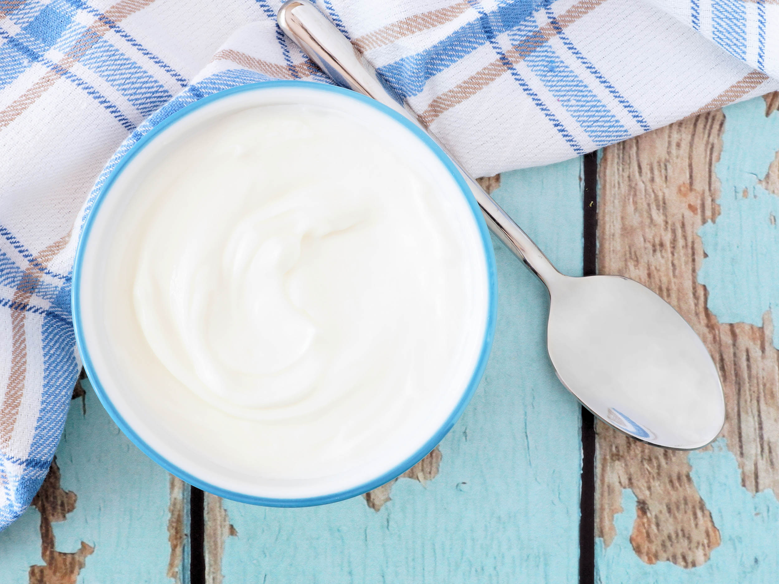 A bowl of plain yoghurt with a pretty blue napkin