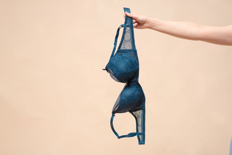 An arm in shot dangling a blue bra