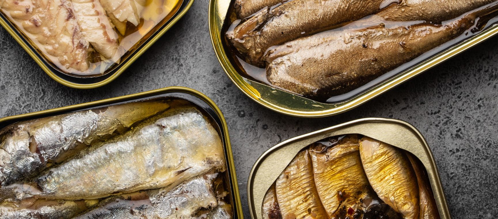 A flat lay shot of various types of tinned fish in their tins