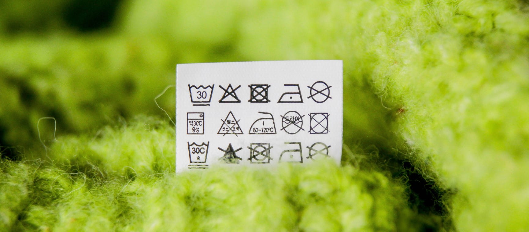 Laundry symbols on a green woollen item of clothing