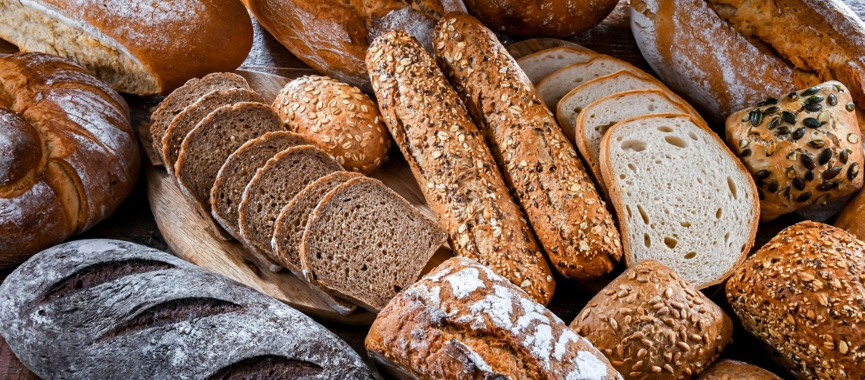 Lots of different types of bread on a wooden surface