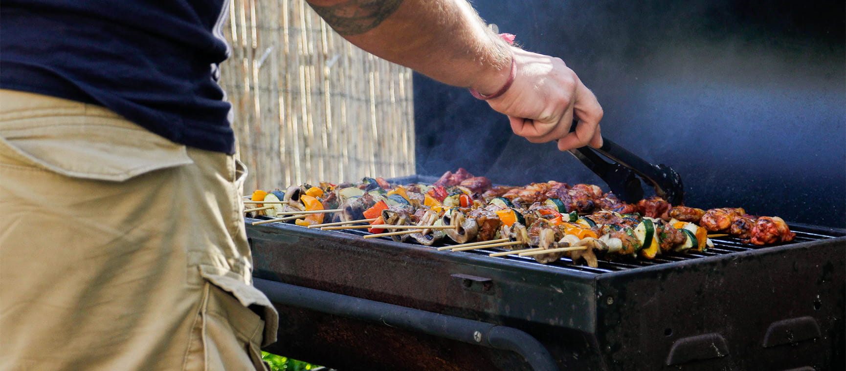 A man grilling kebabs on a barbecue