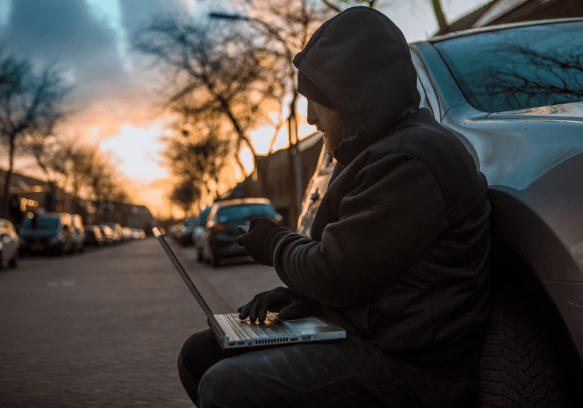 a man with a laptop stealing a car through electronic technology