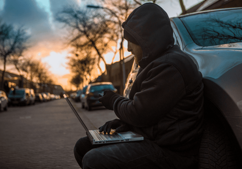 a man with a laptop stealing a car through electronic technology