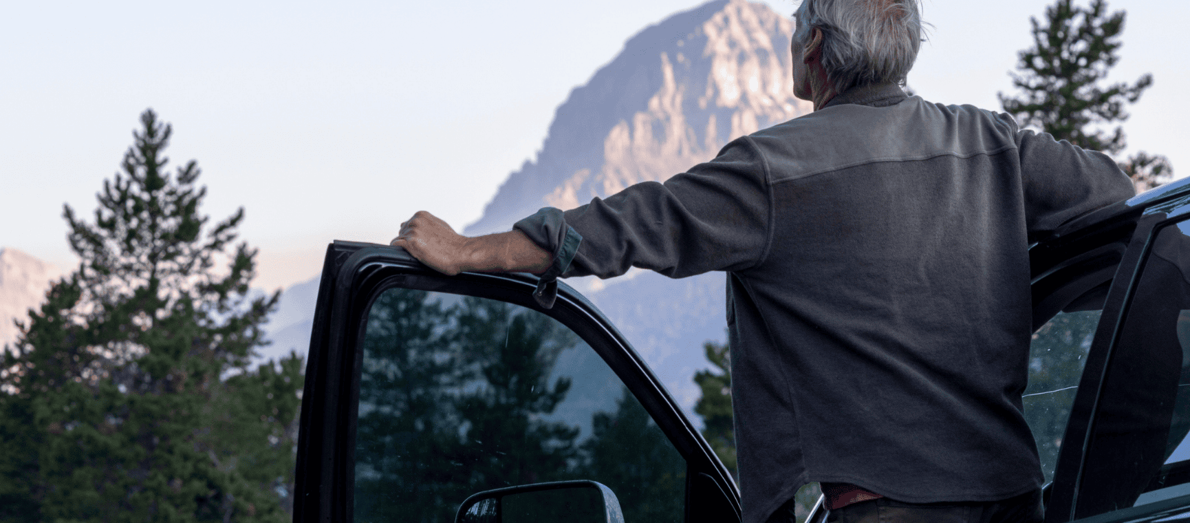 A man with his car door open looking at a stunning mountain