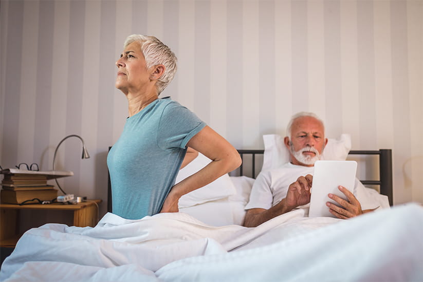 A woman waking up in discomfort next to her husband